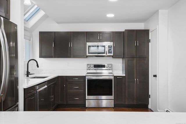 kitchen with a sink, stainless steel appliances, dark wood-style floors, and light countertops