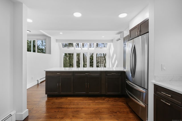 kitchen with a baseboard radiator, a peninsula, light countertops, and freestanding refrigerator