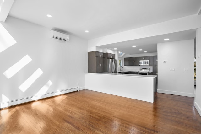 interior space with a wall unit AC, dark wood-style floors, a peninsula, and stainless steel appliances