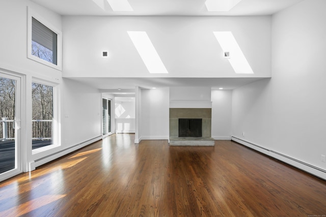 unfurnished living room with a baseboard heating unit, a skylight, and a fireplace with raised hearth