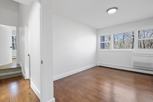 empty room with a baseboard radiator, plenty of natural light, baseboards, and wood finished floors