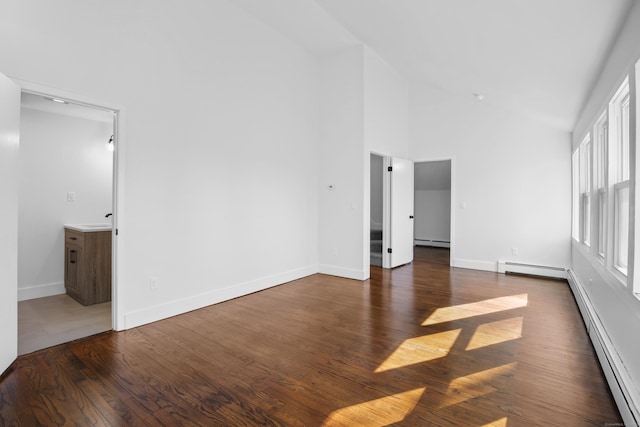 unfurnished room with dark wood finished floors, baseboard heating, and high vaulted ceiling