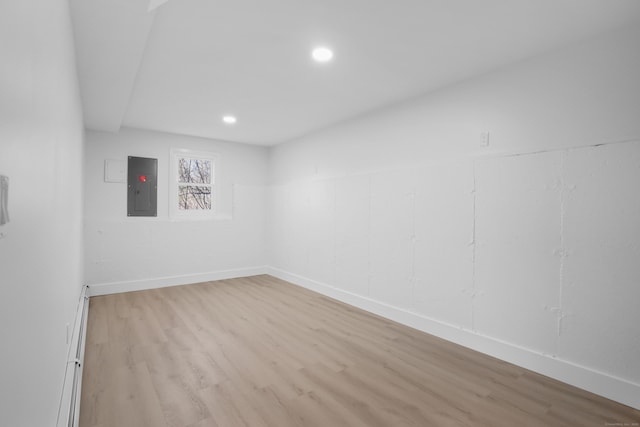 spare room with electric panel, recessed lighting, baseboards, and light wood finished floors