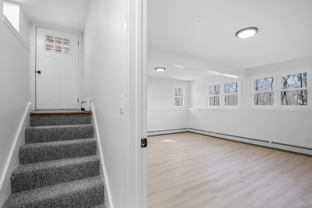 stairway with a baseboard radiator and wood finished floors