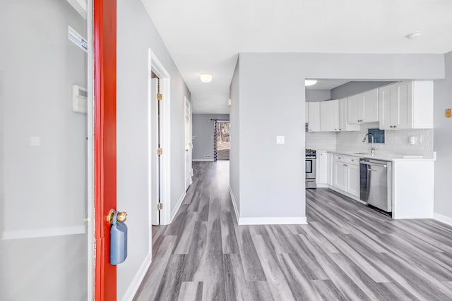 kitchen with light wood finished floors, decorative backsplash, white cabinets, and stainless steel appliances