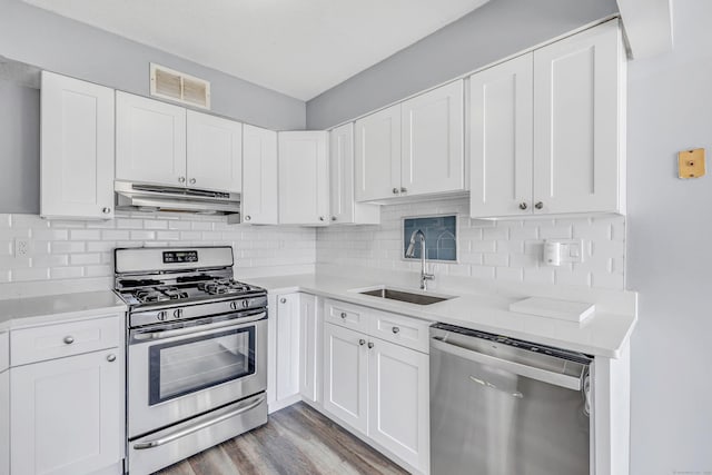 kitchen featuring visible vents, under cabinet range hood, light countertops, appliances with stainless steel finishes, and a sink