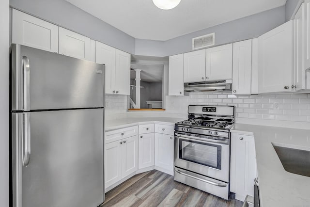 kitchen with wood finished floors, visible vents, light countertops, under cabinet range hood, and appliances with stainless steel finishes