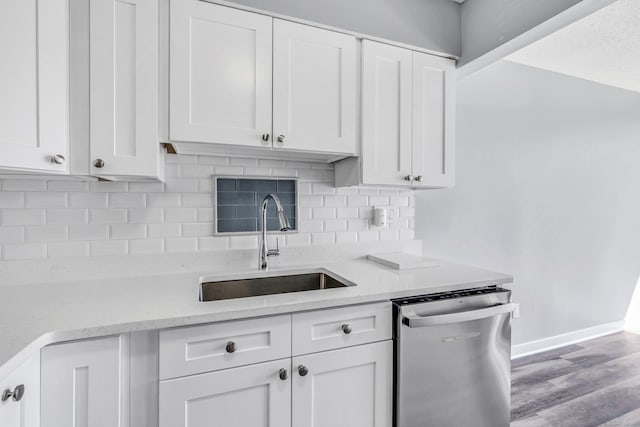 kitchen featuring light stone countertops, decorative backsplash, stainless steel dishwasher, white cabinetry, and a sink