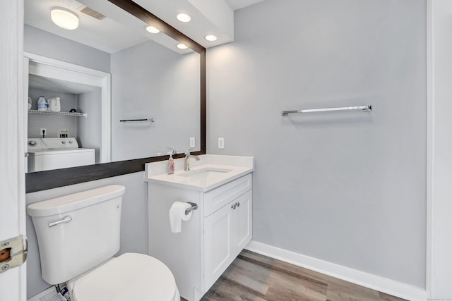 bathroom featuring visible vents, baseboards, toilet, wood finished floors, and washer and dryer