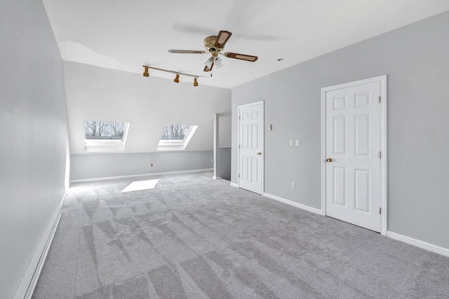 unfurnished bedroom with baseboards, carpet floors, ceiling fan, track lighting, and lofted ceiling with skylight