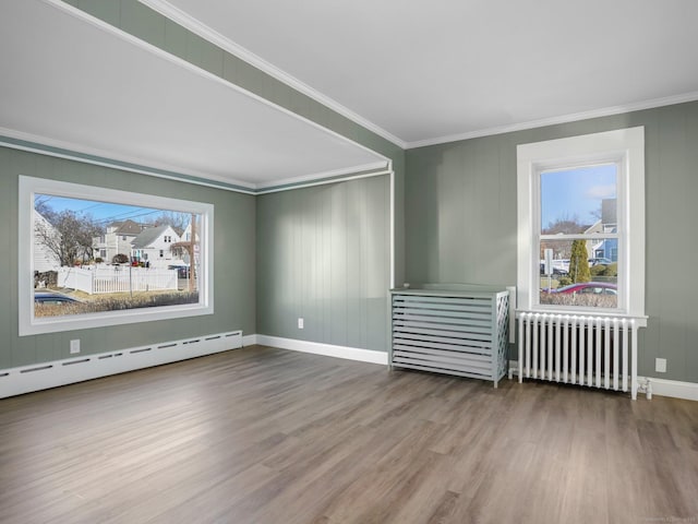 spare room featuring a baseboard heating unit, crown molding, radiator heating unit, and a healthy amount of sunlight