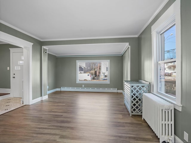 empty room featuring a baseboard heating unit, baseboards, radiator heating unit, ornamental molding, and wood finished floors