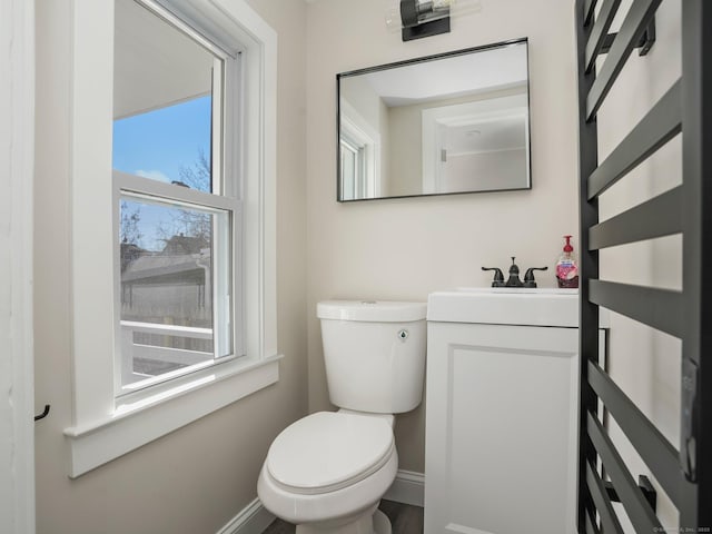 half bath featuring vanity, toilet, and baseboards