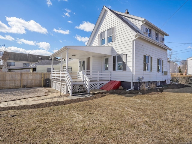 rear view of house featuring a yard, fence, and a chimney