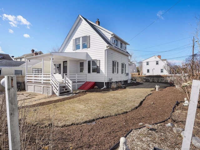 rear view of house with a lawn, covered porch, and a chimney