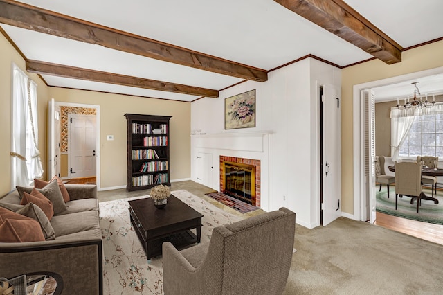 living area with beam ceiling, a notable chandelier, carpet, baseboards, and a brick fireplace