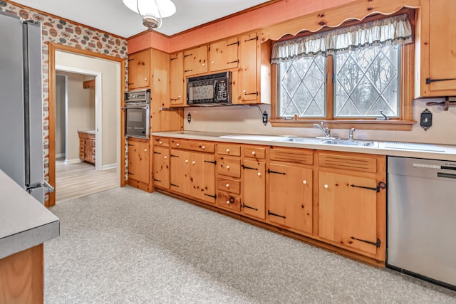 kitchen featuring a sink, baseboards, black appliances, and light countertops