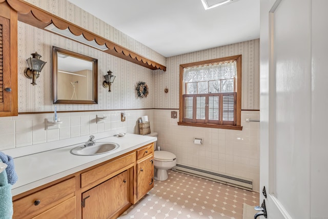 bathroom featuring wallpapered walls, toilet, baseboard heating, and wainscoting