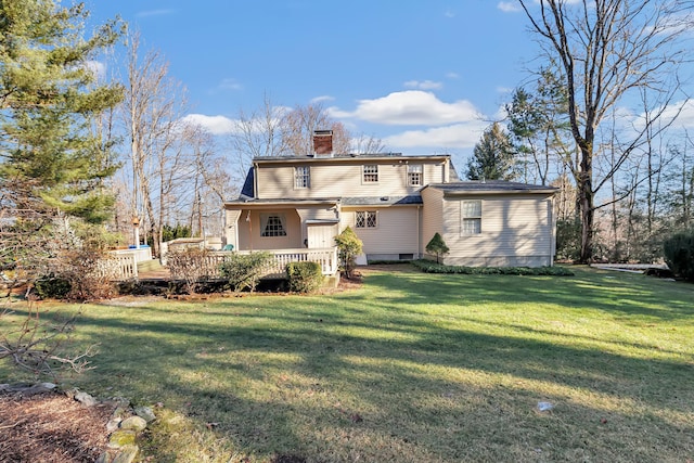 rear view of house with a lawn, a chimney, and a deck