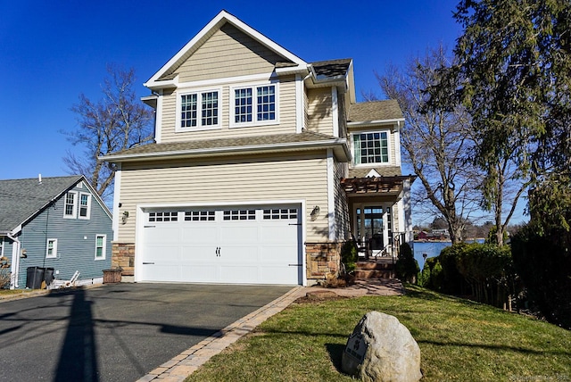 traditional-style home featuring aphalt driveway, a garage, and stone siding