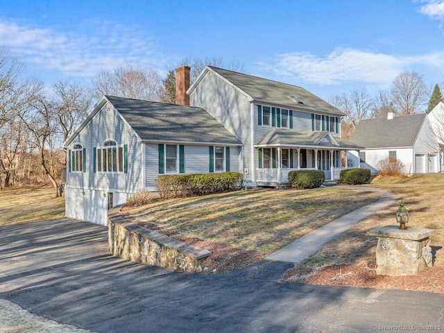 view of front of house with a porch, a garage, driveway, and a chimney