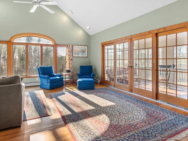 living area with high vaulted ceiling, plenty of natural light, wood finished floors, and a baseboard radiator