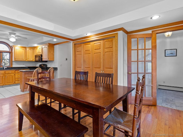 dining room with light wood-style flooring, ornamental molding, recessed lighting, a raised ceiling, and baseboard heating