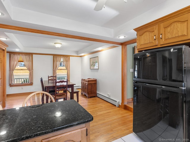 kitchen with light wood-style flooring, dark stone countertops, a tray ceiling, freestanding refrigerator, and baseboard heating