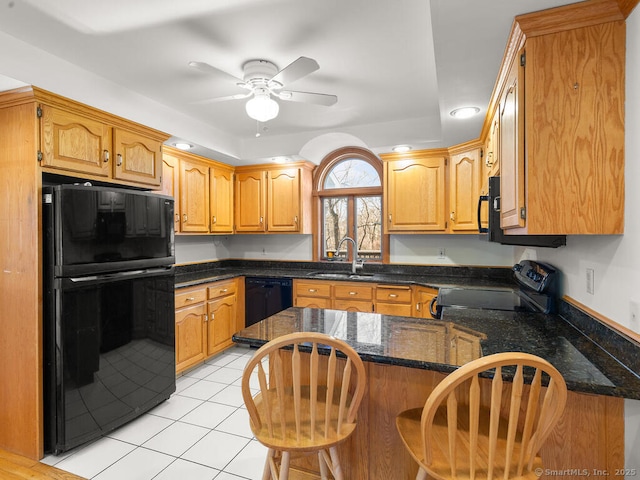 kitchen with a breakfast bar, light tile patterned floors, a peninsula, black appliances, and a sink