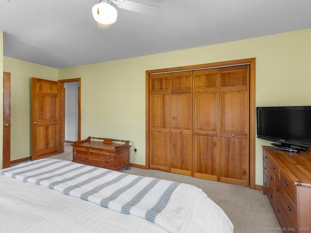 bedroom featuring a closet, baseboards, light colored carpet, and a textured ceiling