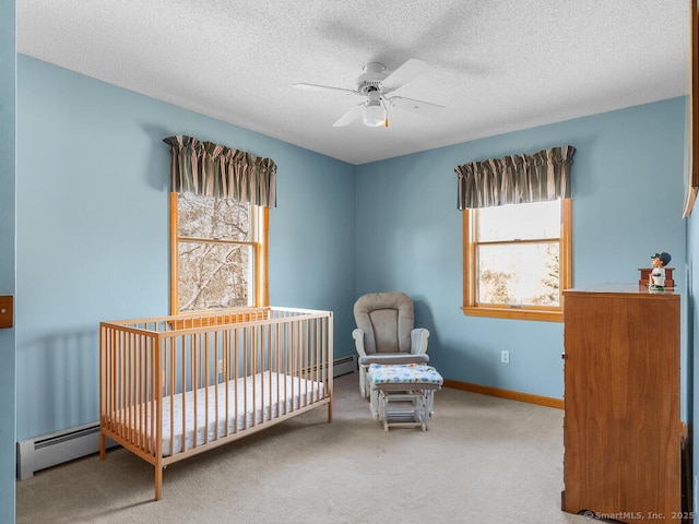 carpeted bedroom featuring a nursery area, multiple windows, baseboard heating, and baseboards