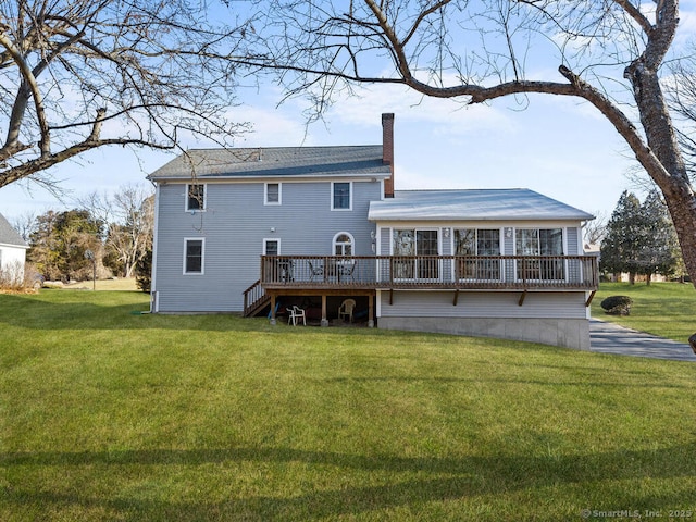 back of property featuring a wooden deck, a lawn, and a chimney