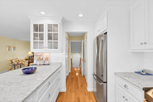 kitchen with white cabinetry, light wood-style flooring, glass insert cabinets, and freestanding refrigerator