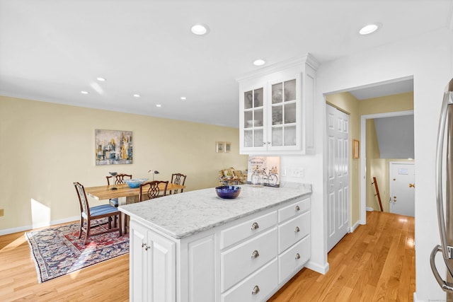 kitchen featuring light wood finished floors, glass insert cabinets, recessed lighting, a peninsula, and white cabinets