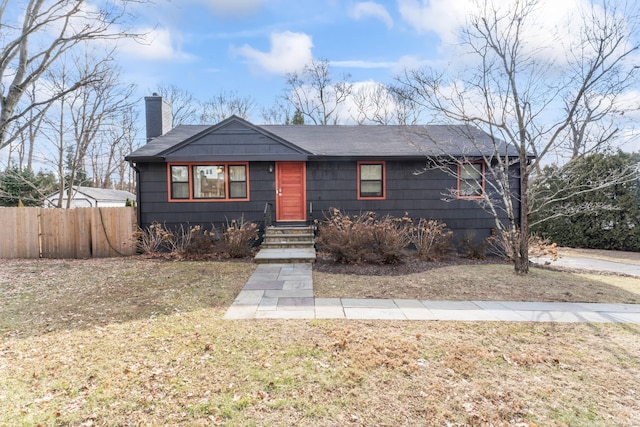 view of front of house featuring a front yard, fence, and a chimney