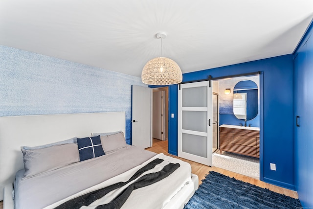 bedroom featuring light wood finished floors and a barn door