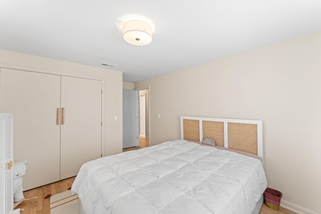 bedroom featuring a closet, visible vents, and wood finished floors