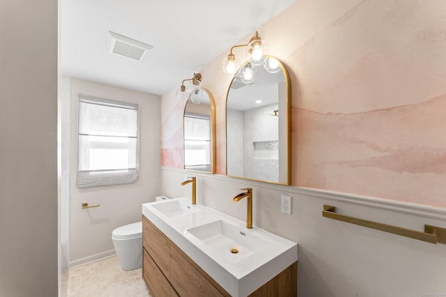 full bath with a sink, visible vents, toilet, and double vanity