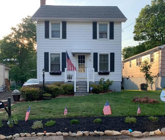 colonial-style house with a chimney and a front lawn