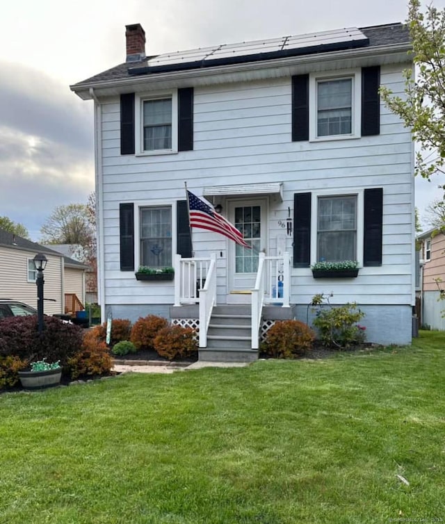 view of front of property featuring solar panels, a front lawn, and a chimney