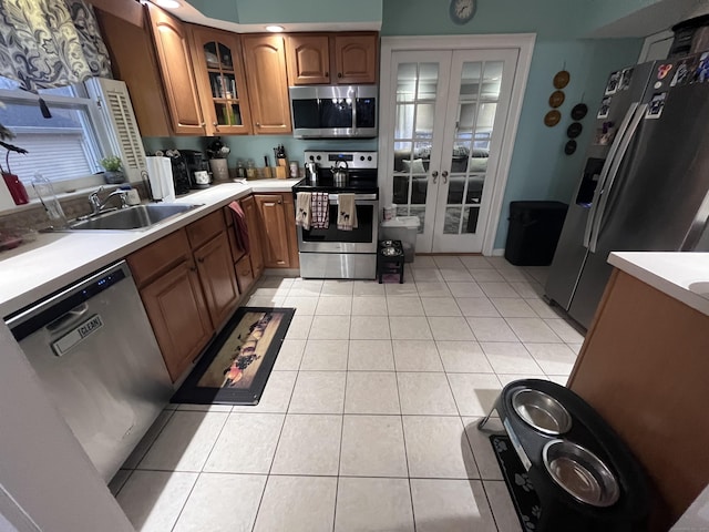 kitchen with light tile patterned floors, brown cabinets, french doors, stainless steel appliances, and a sink