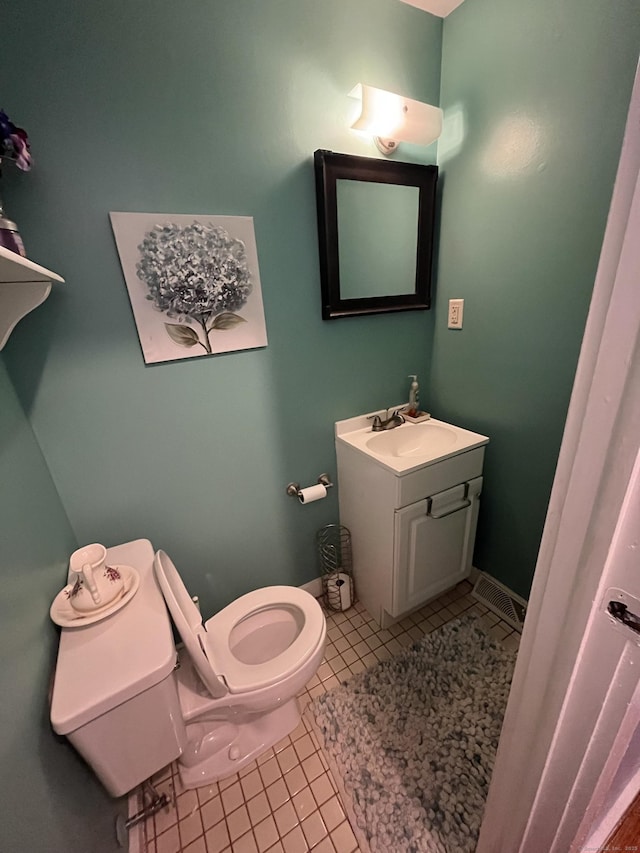 half bath featuring tile patterned floors, toilet, and vanity