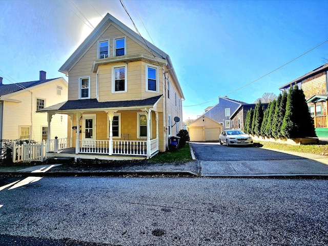 view of front of property featuring a detached garage, covered porch, and an outdoor structure