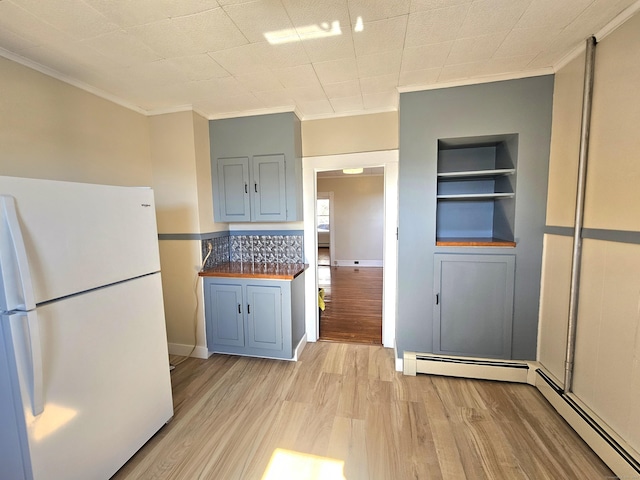 kitchen featuring built in shelves, freestanding refrigerator, light wood-style floors, a baseboard heating unit, and crown molding