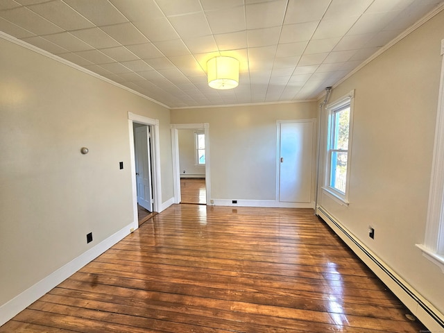 unfurnished room featuring ornamental molding, a baseboard heating unit, a healthy amount of sunlight, and hardwood / wood-style flooring