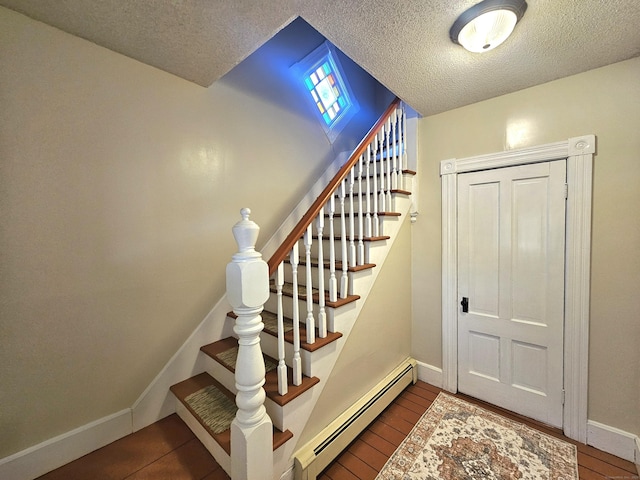 staircase featuring wood finished floors, baseboards, baseboard heating, and a textured ceiling