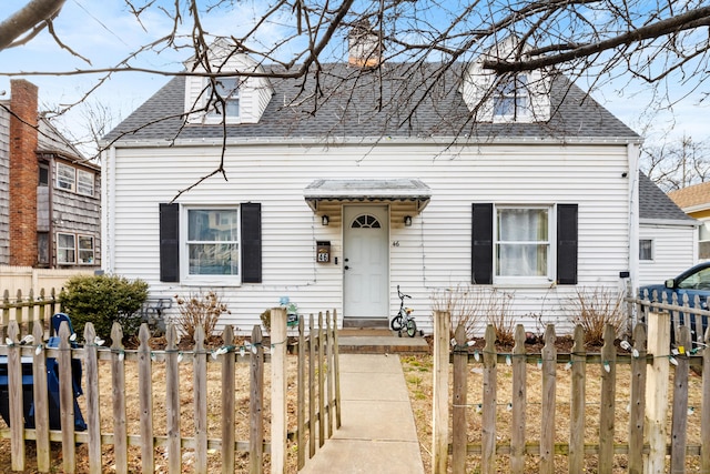 view of front facade featuring a chimney, a fenced front yard, and a shingled roof