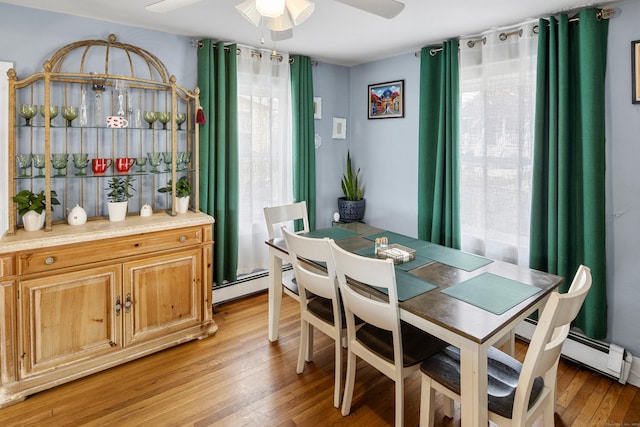 dining space with light wood-style floors, baseboard heating, and ceiling fan