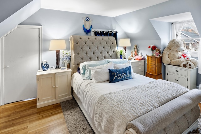 bedroom with vaulted ceiling and light wood-style flooring