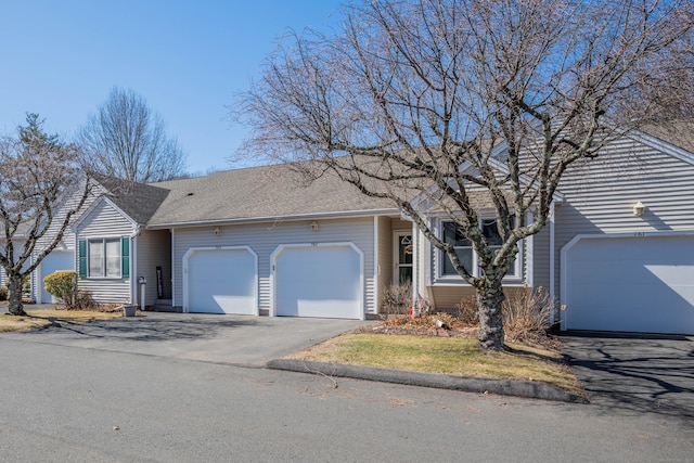 ranch-style house with aphalt driveway, an attached garage, and roof with shingles